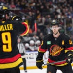 Vancouver Canucks' Elias Pettersson, back right, listens to instructions from J.T. Miller before a faceoff during the first period of an NHL hockey game against the New Jersey Devils in Vancouver, British Columbia, Wednesday, Oct. 30, 2024.
