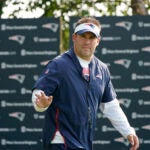 New England Patriots offensive coordinator Josh McDaniels steps on the field at the start of a joint NFL football practice with the New York Giants, Wednesday, Aug. 25, 2021, in Foxborough, Mass.