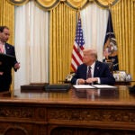 President Donald Trump talks with White House staff secretary Will Scharf as he signs executive orders in the Oval Office of the White House, Thursday, Jan. 23, 2025, in Washington.