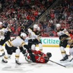 NEWARK, NEW JERSEY - JANUARY 22: The Boston Bruins defend against Nico Hischier #13 and Jack Hughes #86 of the New Jersey Devils during the second period at Prudential Center on January 22, 2025 in Newark, New Jersey.