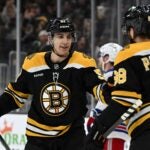 BOSTON, MASSACHUSETTS - FEBRUARY 01: David Pastrnak #88 of the Boston Bruins (R) celebrates with Matthew Poitras #51 after scoring a goal against the New York Rangers during the first period at the TD Garden on February 01, 2025 in Boston, Massachusetts.
