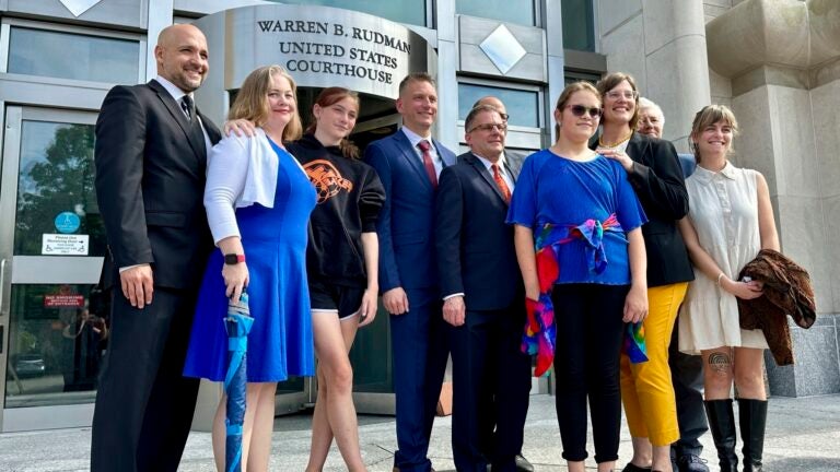 Parker Tirrell, third from left, and Iris Turmelle, sixth from left, pose with their families and attorneys in Concord, N.H.