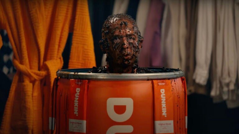 Jeremy Strong emerges from a barrel covered in wet coffee grounds in Dunkin' Super Bowl ad teaser