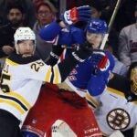NEW YORK, NEW YORK - FEBRUARY 05: Brandon Carlo #25 and Joonas Korpisalo #70 of the Boston Bruins defend against Matt Rempe #73 of the New York Rangers during the first period at Madison Square Garden on February 05, 2025 in New York City.