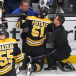 Boston Bruins vs NY Islanders-Boston Bruins center Matthew Poitras (51) was injured after being checked into the Islanders open bench door in the 2nd period.
