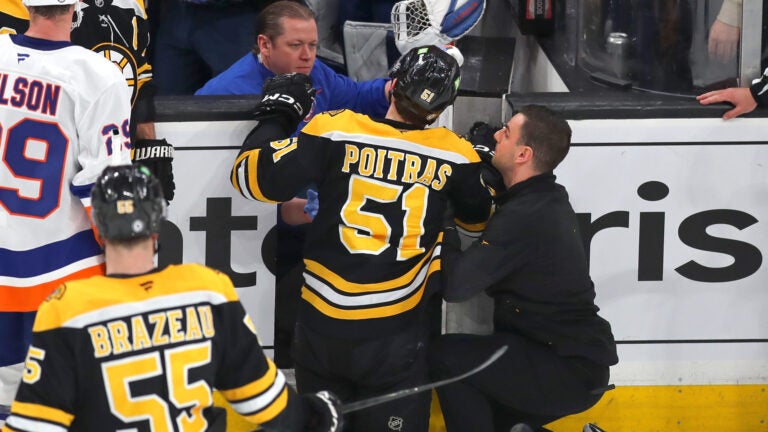 Boston Bruins vs NY Islanders-Boston Bruins center Matthew Poitras (51) was injured after being checked into the Islanders open bench door in the 2nd period.