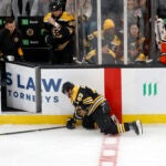 Boston Bruins left wing Brad Marchand (63) crawls to the bench after crashing into the boards as Anaheim Ducks center Mason McTavish (23) looks on during the third period of an NHL hockey game, Saturday, Feb. 22, 2025, in Boston.