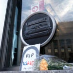 FILE - Flowers and a sign are placed outside the headquarters of the U.S. Agency for International Development, or USAID, Feb. 7, 2025, in Washington. Trump DOGE