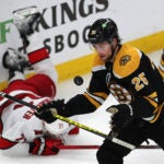 Boston Bruins defenseman Brandon Carlo (25) keeps his eyes on the puck in the 3rd period as Carolina Hurricanes right wing Nino Niederreiter (21) falls behind him.