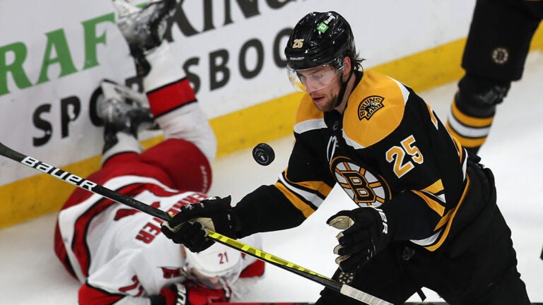 Boston Bruins defenseman Brandon Carlo (25) keeps his eyes on the puck in the 3rd period as Carolina Hurricanes right wing Nino Niederreiter (21) falls behind him.