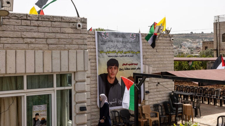A woman walks past a giant poster showing Palestinian American Amer Rabee, 14, who was killed on Sunday.