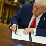 President Donald Trump signs an executive order in the Oval Office.