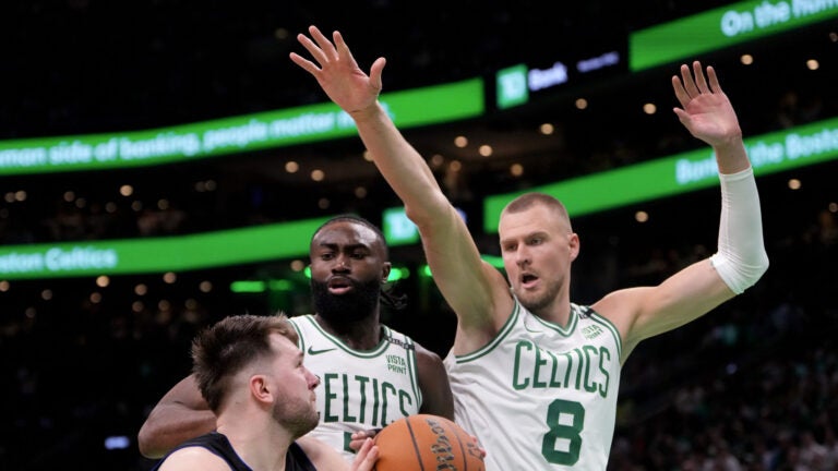 Boston Celtics guard Jaylen Brown (7) and Boston Celtics center Kristaps Porzingis (8) guard Dallas Mavericks guard Luka Doncic (77) during the fourth quarter of Game 1 in the NBA Finals. The Boston Celtics hosted the Dallas Mavericks at TD Garden on Thursday, June 6, 2024.