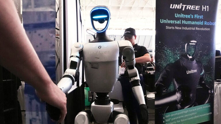 A Unitree robot shakes hands with a convention guest at the Robotics Summit & Expo.
