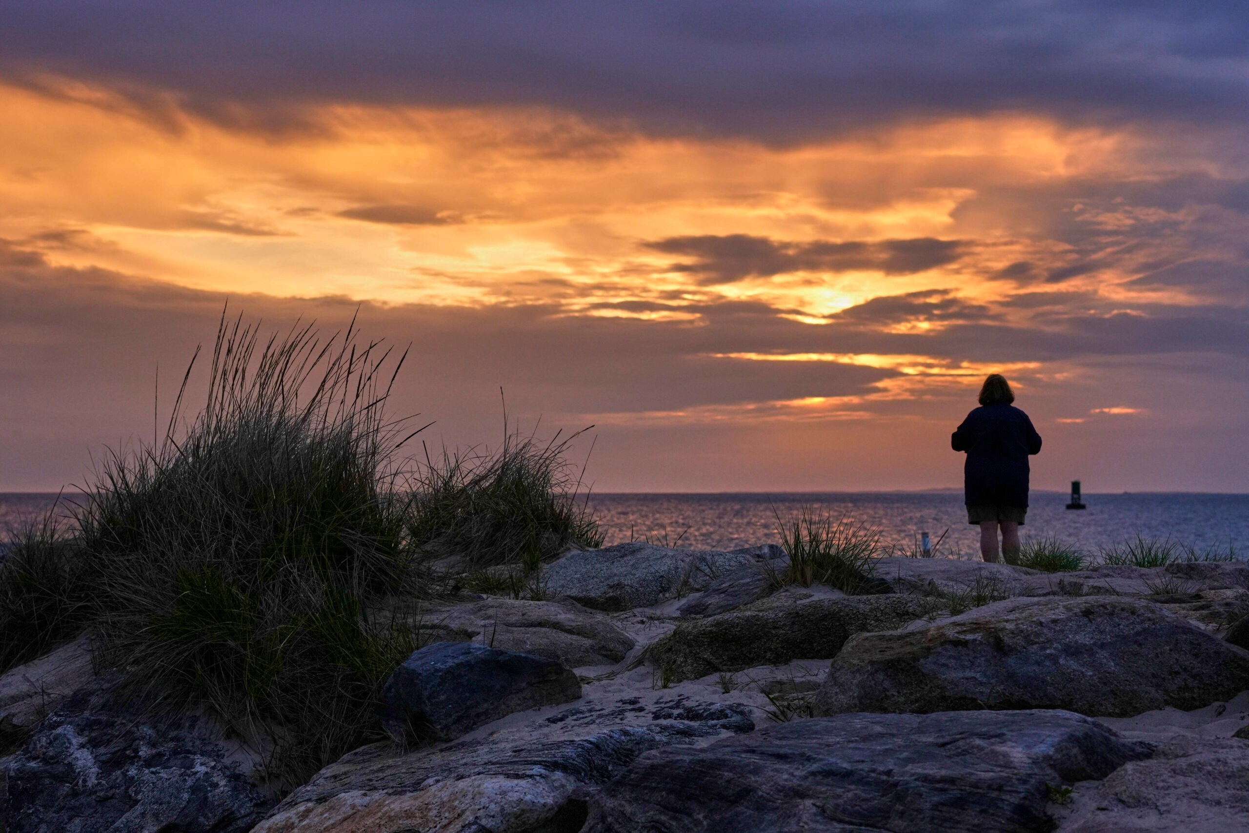 A woman views the sunset at Menemsha Beach. 