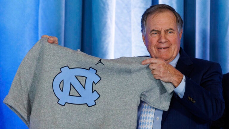 New North Carolina football coach Bill Belichick holds up a UNC branded sleeveless hoodie presented to him during an NCAA college football news conference announcing his hiring, Dec. 12, 2024, in Chapel Hill, N.C.
