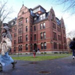FILE - People walk between buildings, Dec. 17, 2024, on the campus of Harvard University in Cambridge, Mass.