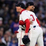 Boston Red Sox pitcher Walker Buehler (0) is held back by catcher Carlos Narvaez while arguing a call by home umpire Mike Estabrook during the third inning of a baseball game against the New York Mets at Fenway Park, Tuesday, May 20, 2025, in Boston.