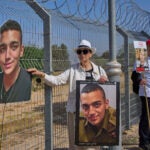 FILE - Varda Ben Baruch holds a picture of her grandson Edan Alexander, who is held hostage in Gaza, gathers with other families to call out on loudspeakers in hopes that their loved ones will hear them, near the Gaza border in Kibbutz Nir Oz, southern Israel, April 20, 2025.