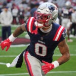 New England Patriots cornerback Christian Gonzalez (0) warms up against the Arizona Cardinals during the first half of an NFL football game, Sunday, Dec. 15, 2024, in Glendale, Ariz.