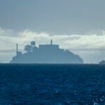 FILE - A boat makes its way toward Alcatraz Island with the San Francisco-Oakland Bay Bridge in the background in this view from Sausalito, Calif., Dec. 13, 2023.