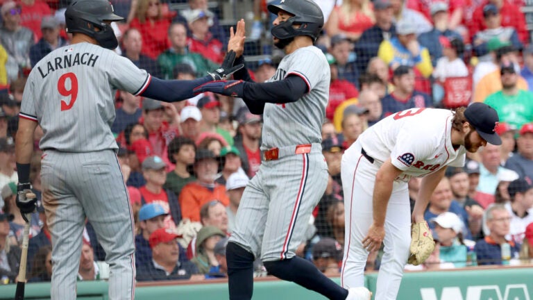 Red Sox pitcher Justin Slaten reacts as Twins shortstop Carlos Correa high-fives Trevor Larnach after scoring during the eighth inning.