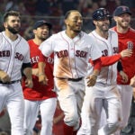 Following the game winning run scoring on a throwing error, the Red Sox (left to right) Mitch Moreland Nathan Eovaldi, Mookie Betts, J.D. Martinez (who scored the winning run) and Chris Sale are all smiles as thy head to celebrate with teammate Eduardo Nunez, who was safe at first base on the play. The Boston Red Sox hosted the Miami Marlins in a regular season inter league MLB baseball game at Fenway Park.