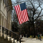 An American flag flies over the John Harvard statue at Harvard University in Cambridge.