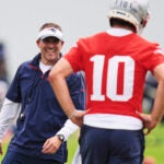 New England Patriots offensive coordinator Josh McDaniels smiles while talking with quarterback Drake Maye (10) during an NFL football practice, Wednesday, May 28, 2025, in Foxborough, Mass.