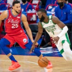 Boston Celtics' Jaylen Brown, right, drives to the basket against Philadelphia 76ers' Ben Simmons, left, during the first half of an NBA basketball game, Friday, Jan. 22, 2021, in Philadelphia.