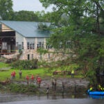 Rescue workers are seen on land and on a boat as they search for missing people near Camp Mystic along the Guadalupe River after a flash flood swept through the area Sunday, July 6, 2025, in Hunt, Texas.