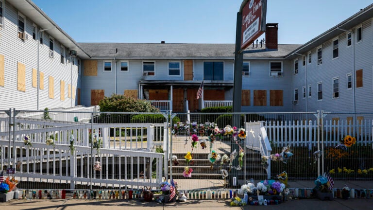Flowers, photographs and memorial items are placed along the chain-link fence surrounding Gabriel House assisted living facility in Fall River.