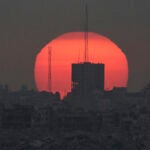 The sun sets over damaged buildings in the Gaza Strip, seen from southern Israel, Tuesday, July 1, 2025.