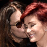 FILE - Ozzy Osbourne kisses his wife Sharon during the "Ozzfest Meets Knotfest" news conference at the Hollywood Palladium, May 12, 2016, in Los Angeles.