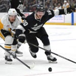 Pittsburgh Penguins defenseman Matt Grzelcyk, left, and Los Angeles Kings left wing Tanner Jeannot go for the puck during the second period of an NHL hockey game Monday, Jan. 20, 2025, in Los Angeles.