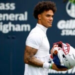 Patriots cornerback Christian Gonzalez (0) walks onto the field for the OTA offseason workouts at Gillette Stadium on May 28, 2025.