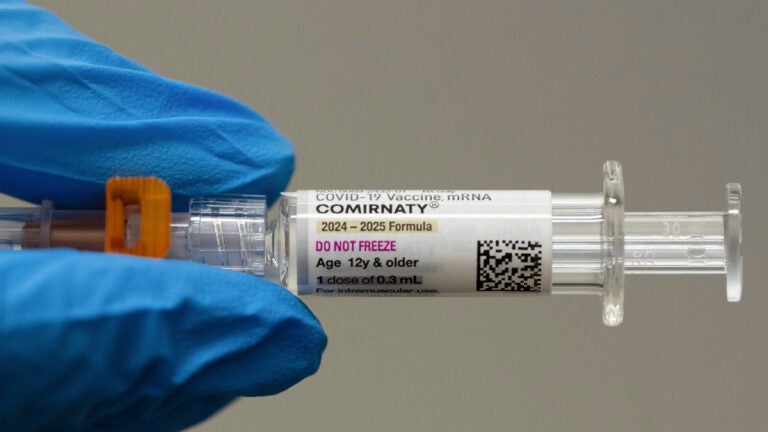 A pharmacist holds a Pfizer and BioNTech COVID-19 vaccine shot.