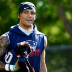 New England Patriots cornerback Christian Gonzalez (0) carries a puppy onto the field for the New England Patriots Foundation’s pet adoption day on day one of NFL training camp at Gillette Stadium on July 23, 2025.