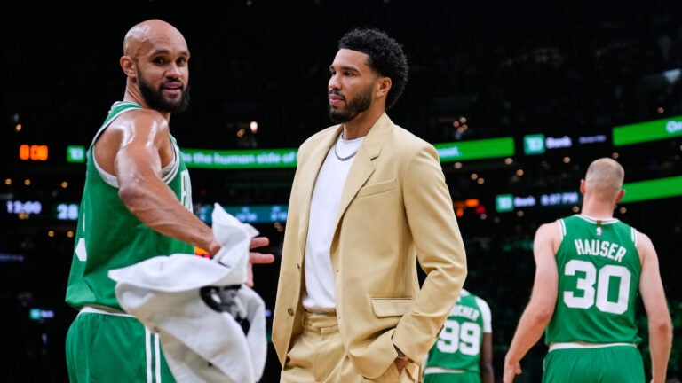 Boston Celtics forward Jayson Tatum, center, talks with guard Derrick White, left, during a time out in the first half of an NBA basketball game, Wednesday, Oct. 22, 2025, in Boston.