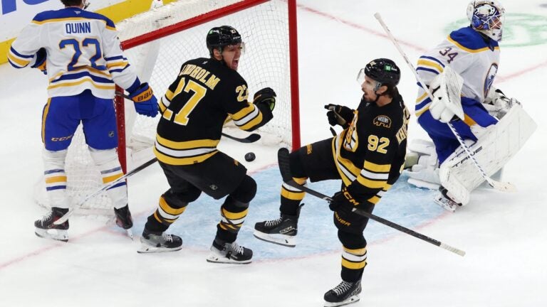 Boston Bruins' Marat Khusnutdinov (92) celebrates his goal on Buffalo Sabres' Alex Lyon with teammate Hampus Lindholm (27) in overtime during an NHL hockey game, Thursday, Oct. 30, 2025, in Boston.