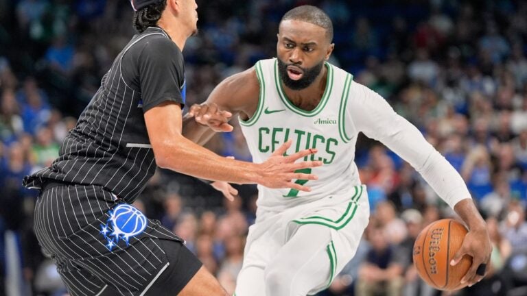 Jaylen Brown pushes through an Orlando Magic defender while dribbling a basketball during a game.
