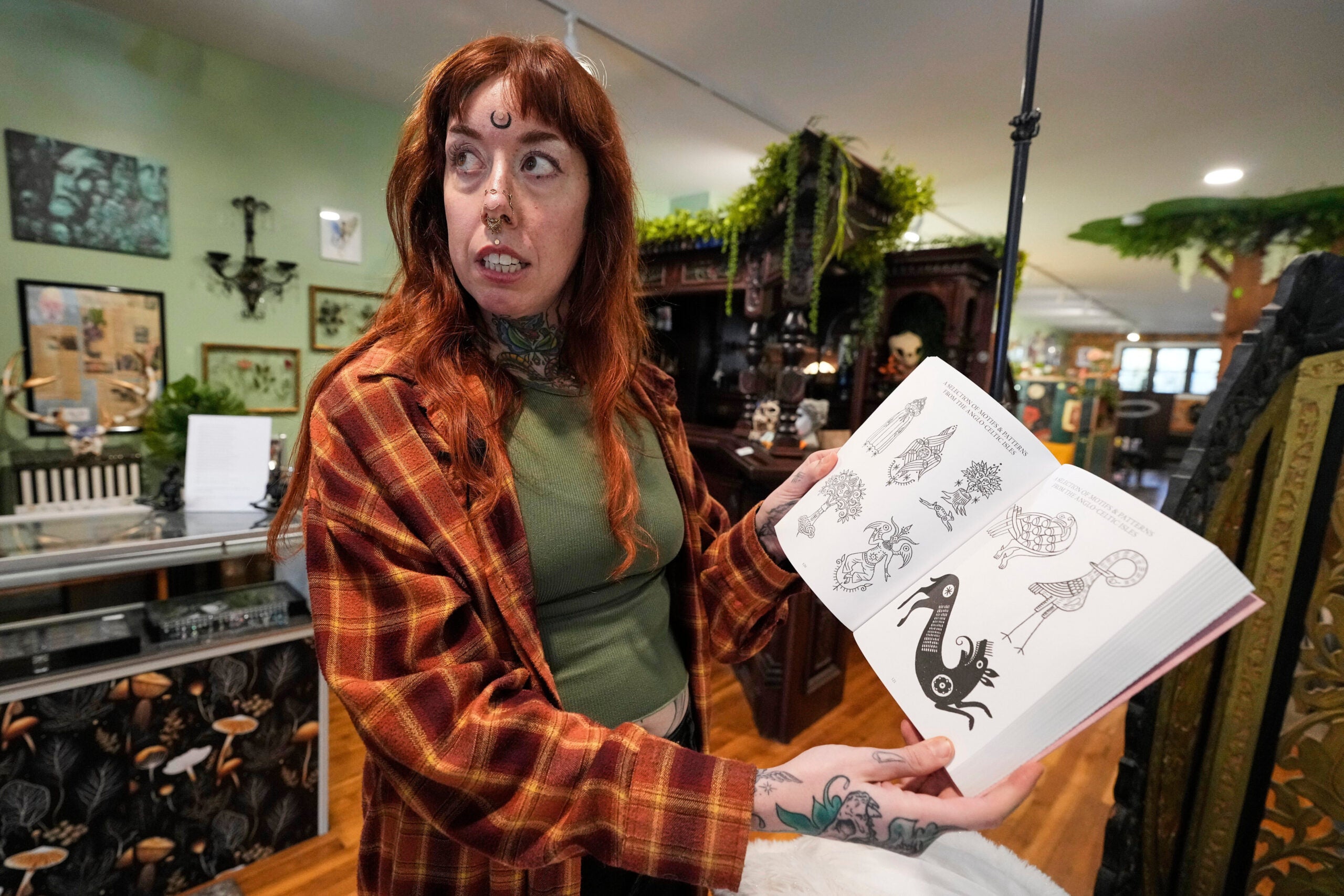Tattoo artist Mischa Ostberg shows a visitor a selection of Anglo-Celtic patterns, Nov. 3, 2025, in Ellsworth, Maine. 