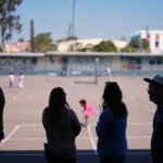 Teachers look on as students play on the playground at Perkins K-8 School.