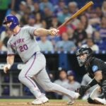 Pete Alonso takes a swing during a game and watches the ball as he's about to exit the batter's box.