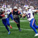 Buffalo Bills quarterback Josh Allen (17) runs against New England Patriots cornerback Christian Gonzalez (0) and safety Jaylinn Hawkins (21) during the second half of an NFL football game in Foxborough, Mass., Sunday, Dec. 14, 2025.