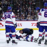 United States defenseman Cole Hutson, bottom, is looked at by medical staff after sustaining an injury as members of the United States team look on during the second period of an IIHF World Junior Hockey Championship game against Switzerland, Saturday, Dec. 27, 2025, in St. Paul, Minn.