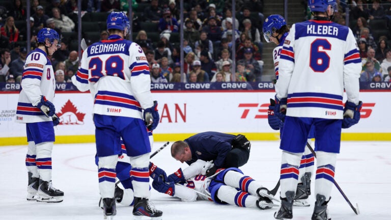 United States defenseman Cole Hutson, bottom, is looked at by medical staff after sustaining an injury as members of the United States team look on during the second period of an IIHF World Junior Hockey Championship game against Switzerland, Saturday, Dec. 27, 2025, in St. Paul, Minn.