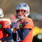 The NE Patriots practiced on their practice field at Gillette Stadium. QB Drake Maye walks along the field during stretching.