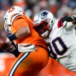 New England Patriots defensive tackle Christian Barmore (90) sacks Denver Broncos quarterback Russell Wilson (3), knocking the ball out of Wilson’s hands in the second half. The Patriots defeat the Broncos, 26-23, at Empower Field at Mile High.