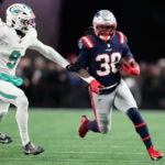 New England Patriots running back Rhamondre Stevenson, right, runs against Miami Dolphins safety Ifeatu Melifonwu during the second half of an NFL football game in Foxborough, Mass., Sunday, Jan. 4, 2026.